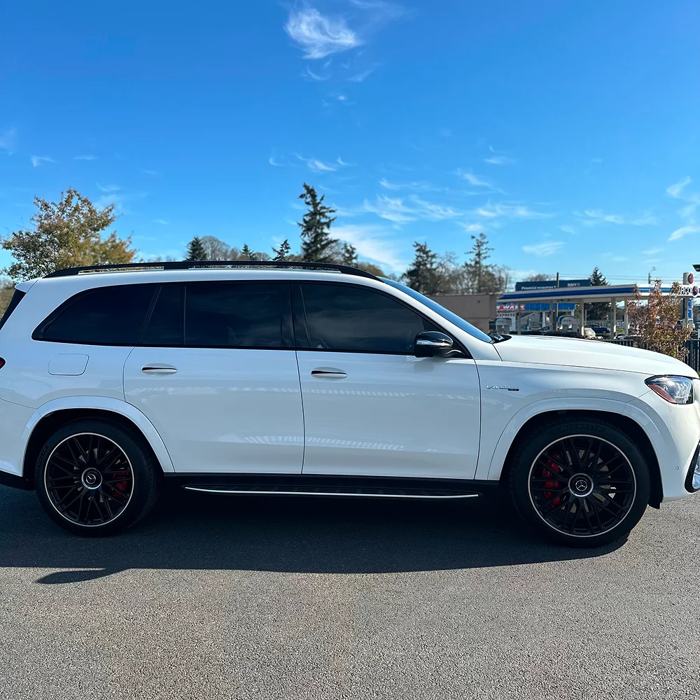 White Mercedes-AMG SUV with blacked-out window tint and red brake calipers parked on sunny day