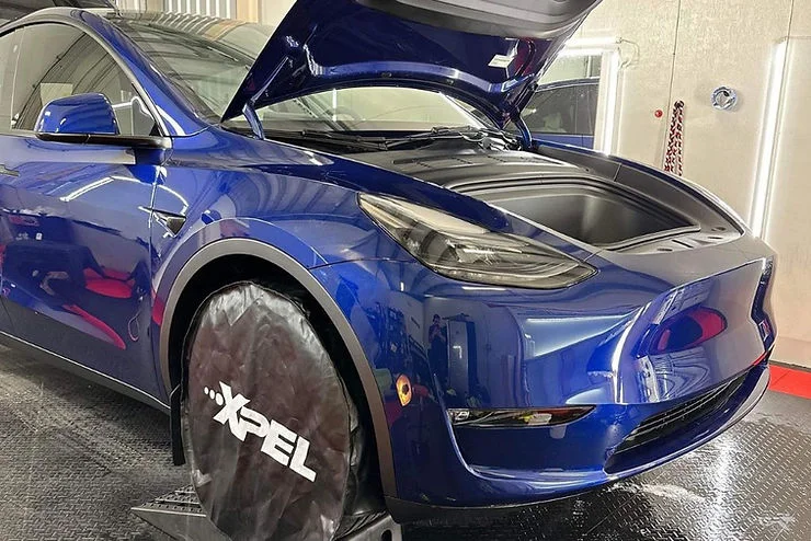 Blue Tesla undergoing curing process after paint protection application at a detailing shop