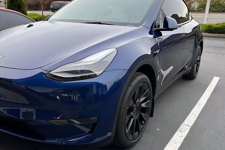 Glossy blue electric SUV parked in a lot, reflecting its surroundings after a ceramic coating