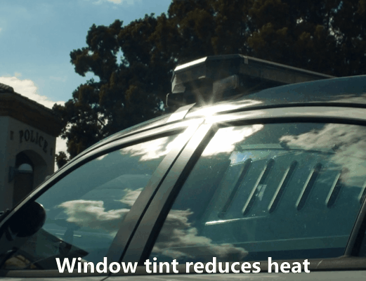 Close-up of a car window with dark tint reflecting sunlight, demonstrating reduced glare and heat protection