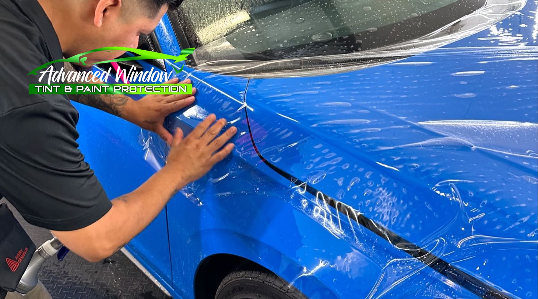 Technician applying paint protection film (PPF) to a blue vehicle at Advanced Window Tint & Paint Protection in Tacoma, WA