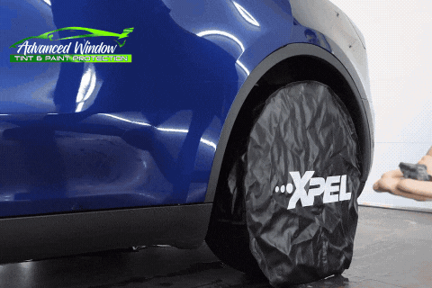 Detailer applying paint protection film to a blue car fender using a heat gun at Advanced Window Tint & Paint Protection