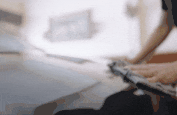 Close-up of a person applying paint protection to a car hood with a soft cloth, enhancing its shine