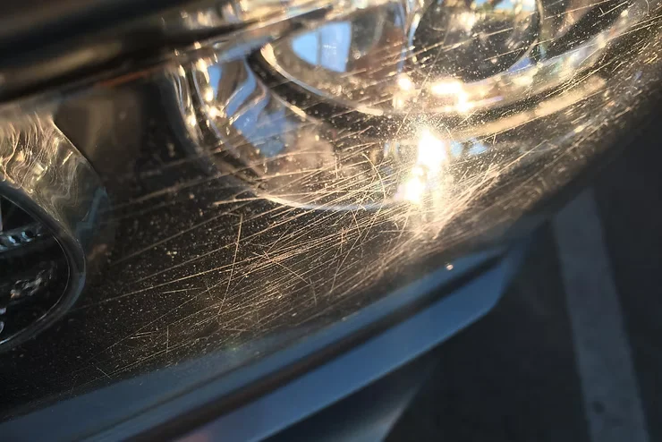 Close-up of a vehicle headlight showing visible scratches, cloudiness, and surface wear from road debris and UV exposure — highlighting the need for paint protection film in Tacoma’s wet and UV-intense climate.