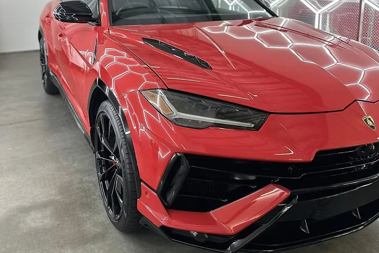Front view of a red Lamborghini SUV with clean, protected headlights and a flawless glossy finish, illustrating the long-lasting performance of professionally installed headlight PPF in preserving clarity and style.