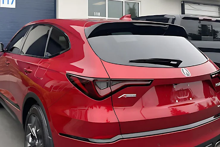 Rear view of a red SUV with dark tinted windows parked outside a building, demonstrating the privacy and sun protection benefits of professional car window tinting in Tacoma, Washington.