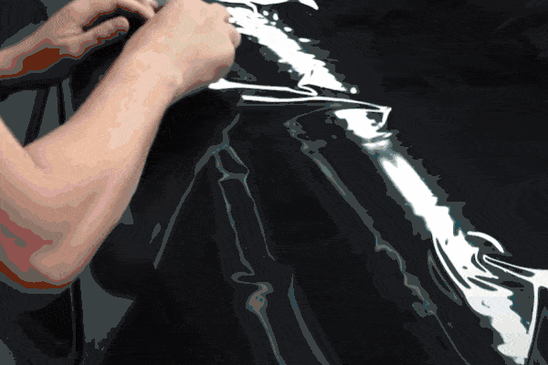 Person polishing a tinted car window with an orange microfiber cloth during ceramic tint installation