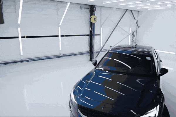 Technician applying paint protection film (PPF) to the front of a vehicle to shield it from damage