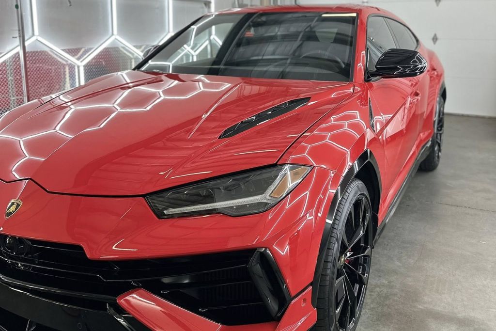 Red Lamborghini SUV with a flawless, high-gloss finish reflecting hexagonal studio lighting, showcasing the results of a professional ceramic coating application.