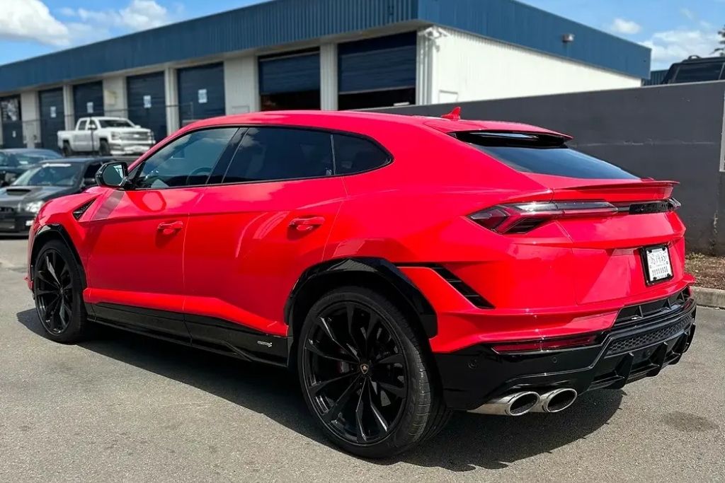 Red SUV with dark tinted windows parked outside an auto shop, showcasing professional automotive window tint installation.