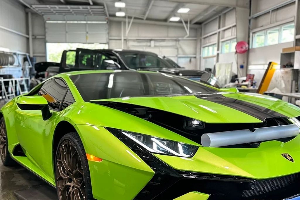 Bright green sports car with dark window tint inside an automotive tint and protection shop