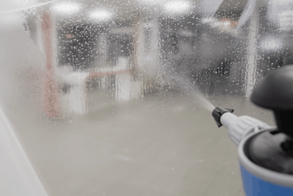 Spraying solution on paint protection film during installation to help apply clear PPF smoothly on a vehicle surface.
