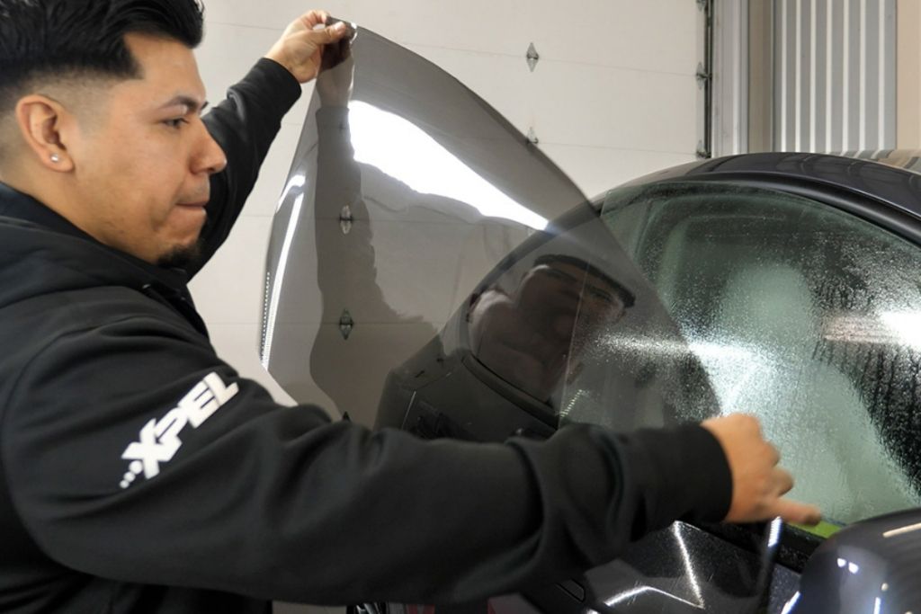 Technician applying window tint film to a vehicle side window during professional auto tint installation in Tacoma, WA