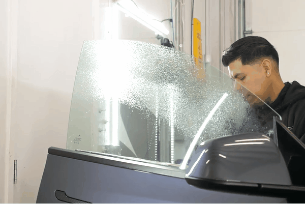 Technician preparing a vehicle side window for professional auto window tint installation in Tacoma, WA