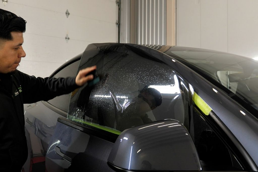 Technician installing ceramic window tint on a vehicle window at a Tacoma automotive tint shop.