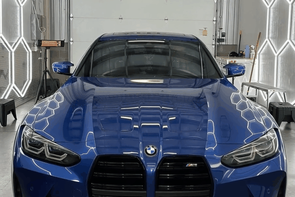 Blue BMW sports coupe with a high-gloss finish inside a professional automotive detailing and paint protection shop